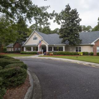A suburban house with a driveway, surrounded by trees and a well-kept lawn.