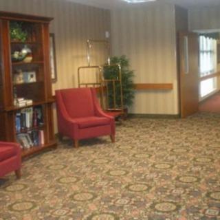 A cozy lobby area with red chairs and a bookshelf.