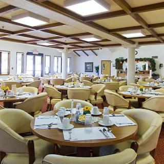 A spacious and well-lit restaurant dining area with neatly arranged tables and comfortable seating.