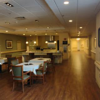 A well-lit dining area with tables and a kitchen in the background.