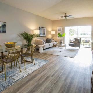 A modern living room with a connected dining area featuring chic decor and ample natural light.