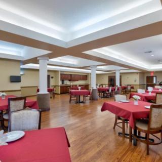 A spacious dining room with red tablecloths and wood flooring.