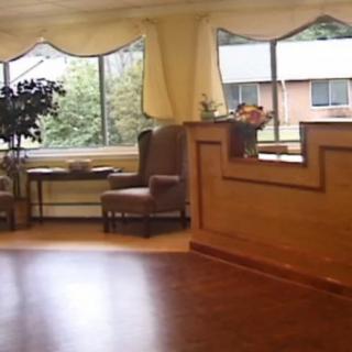 A cozy lobby area with a large window, armchair, and reception desk.