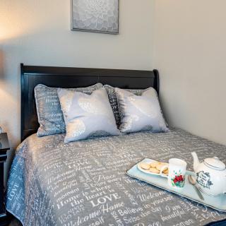 A cozy bedroom featuring a bed with patterned bedding, two pillows, and a tray with a tea set.