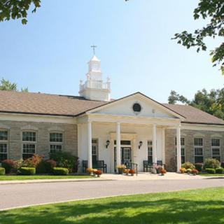 A classic building with columns and a cupola, surrounded by a well-maintained lawn and trees.