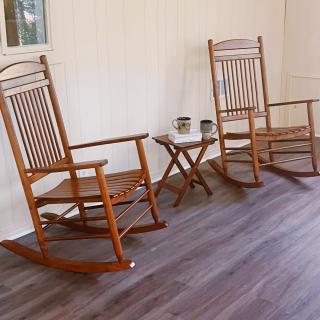 Two wooden rocking chairs and a small table on a porch.