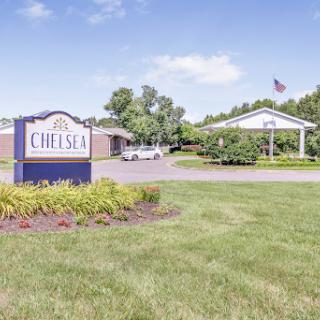 Entrance to Chelsea, showcasing well-maintained landscaping and a clear blue sky.