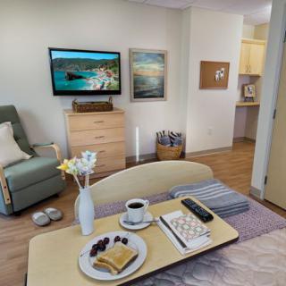 A cozy living room with a set breakfast on the coffee table and a television mounted on the wall.