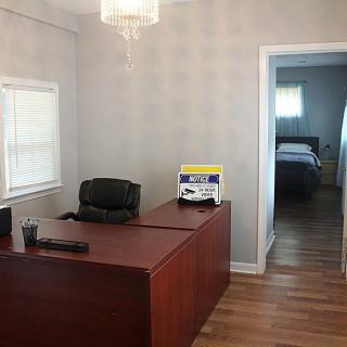 A simple office setup with a desk and chair, adjacent to a room.