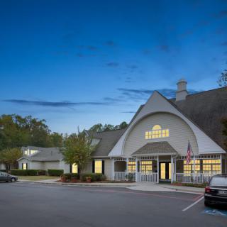A well-lit building with a parking lot at dusk.