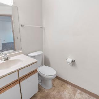 A clean and simple bathroom featuring a toilet and sink with neutral-toned walls.