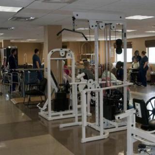 A spacious gym area filled with various exercise equipment and people working out.