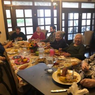 A family gathering around a dinner table, enjoying a meal together.