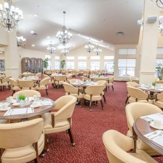 A spacious and elegantly decorated dining room with round tables and comfortable chairs.