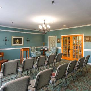 A neatly arranged meeting room with rows of chairs facing a podium, set in an elegantly decorated interior.