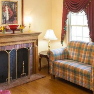 A cozy living room featuring a fireplace and plaid couch with elegant curtains.