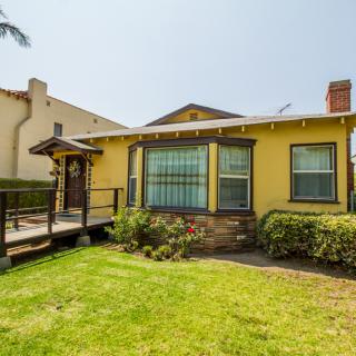 A charming yellow house with a well-kept lawn and garden.