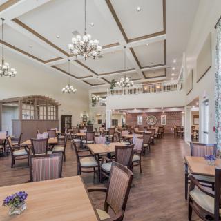A spacious, elegantly designed dining room with wooden tables and chairs, adorned with chandeliers.