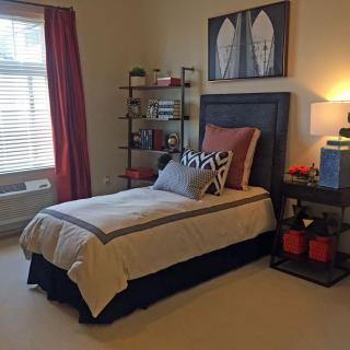A neatly arranged bedroom with a single bed, shelving, and stylish decor.