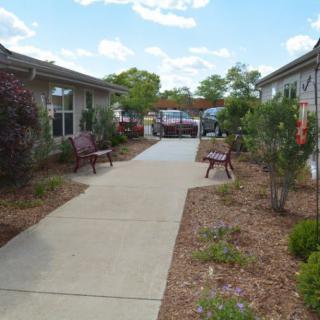 A tranquil outdoor pathway with benches and landscaped gardens on either side.