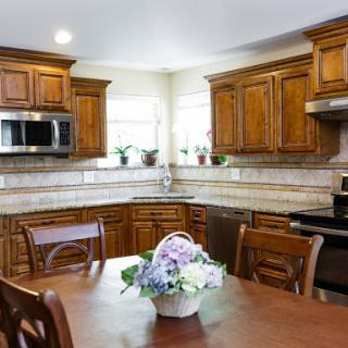 A cozy kitchen featuring elegant wooden cabinets and a dining area adorned with fresh flowers.