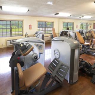 A gym room with various exercise machines and workout equipment.