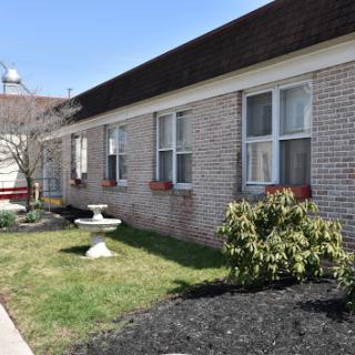 A well-maintained brick building featuring large windows and landscaped greenery.