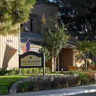 A view of a building with a sign and American flag, surrounded by trees.