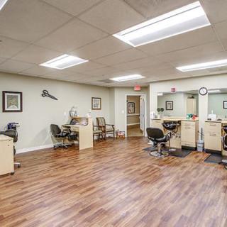 An interior view of a salon with multiple styling stations and wooden flooring.