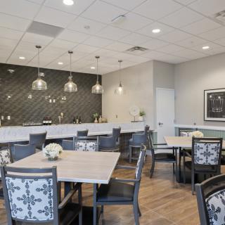 A modern dining area with stylish tables and chairs, featuring pendant lighting and a decorative wall.