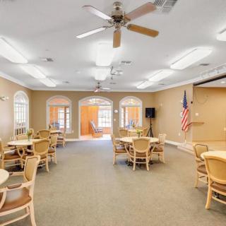 A spacious meeting room with tables and chairs, ceiling fans, and an American flag.
