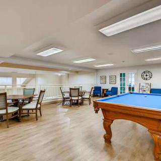A spacious recreation room featuring a pool table and seating area.