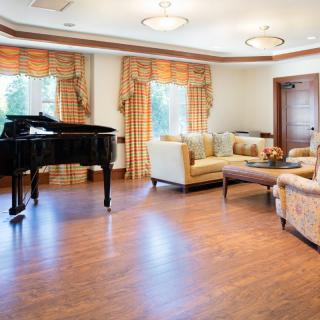 A spacious living room featuring a grand piano and elegant furniture.