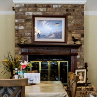 A cozy dining area with a brick fireplace, adorned with artwork and decorative elements.