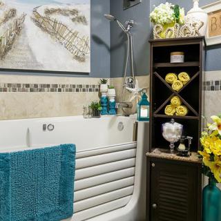 A modern bathroom with a decorative bathtub, vibrant towels, and a stylish shelving unit adorned with flowers and decor.