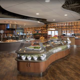 A modern cafeteria with a buffet-style food display and warm lighting.