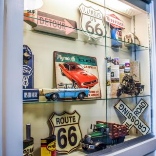 A display case filled with vintage collectibles, featuring Route 66 signs and miniature classic cars.