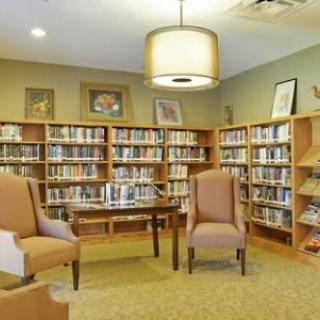 A cozy library reading area with bookshelves, chairs, and a table.