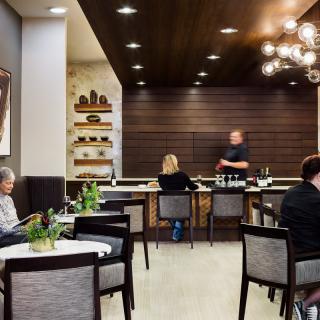 A cozy cafe interior with people sitting at tables and a bar area in the background.