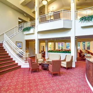 A spacious lobby with a staircase, comfortable seating, and vibrant carpet.