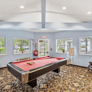 A well-lit game room featuring a pool table and large windows.