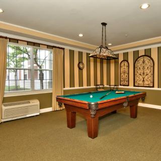 A cozy billiard room with a pool table and stylish striped wallpaper.