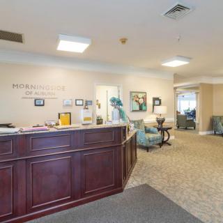 A reception area with a wooden desk and seating in an office environment.