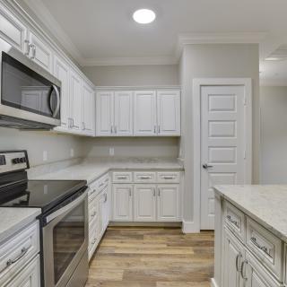 A modern kitchen with white cabinets and stainless steel appliances.