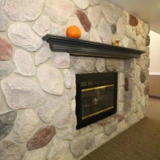 A cozy stone fireplace with a pumpkin on the mantel, adding a touch of autumn decor.