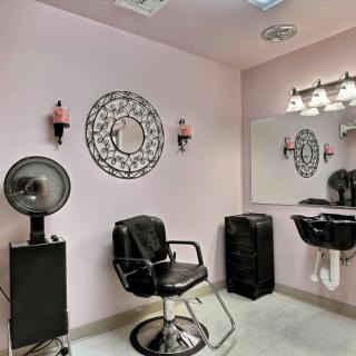 A cozy salon interior with a styling chair, mirror, and hair drying station.
