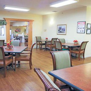 A spacious and neatly arranged dining area with wooden tables and upholstered chairs.