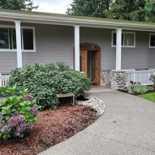 A cozy house entrance with a landscaped garden and curved pathway.