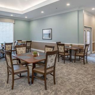 A neatly arranged dining room with several tables and chairs on a carpeted floor.