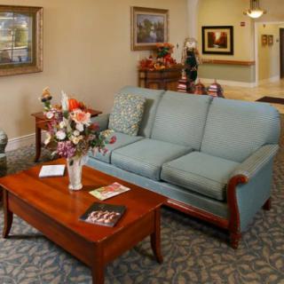 A cozy living room with a blue sofa and wooden coffee table, adorned with flowers and artwork on the walls.